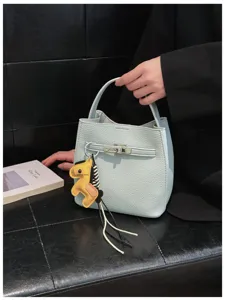 Schicke hellblaue Leder Eimer Handtasche mit Metallschloss und gelbem Pferd Anhänger.