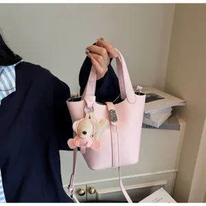 Bolso tipo cubo rosa con textura litchi, asa superior, correa y lindo colgante elegante.