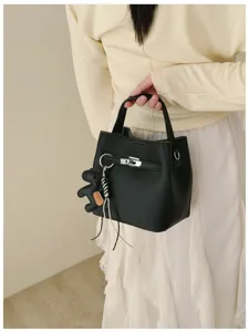 Detailaufnahme der schwarzen Leder-Eimertasche mit Drehverschluss und Bären-Anhänger.