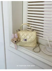 Detailed view of fashionable quilted yellow shoulder bag showcasing chain strap and cute bear pendant.
