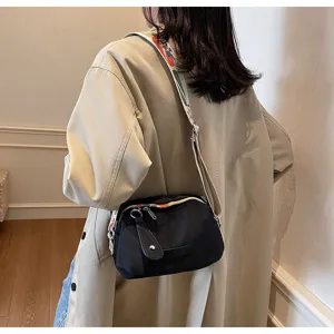 Detailopname van een zwarte oxford stoffen crossbody tas met een kleurrijke band.