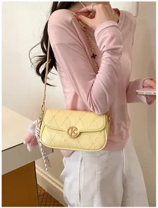 Vista detallada del elegante bolso acolchado amarillo con cadena dorada y trébol.