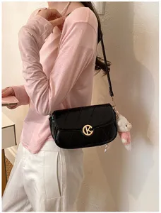 Bolso de hombro acolchado negro con cadena dorada, cierre K de metal y colgante de oso.