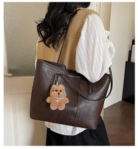 Borsa tote marrone in stile retrò nel dettaglio, con un grazioso ciondolo a forma di orsetto.