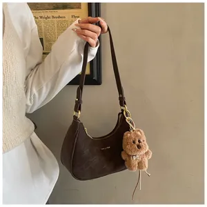 Detailed view of the stylish brown suede shoulder bag featuring a cute fluffy bear keychain.
