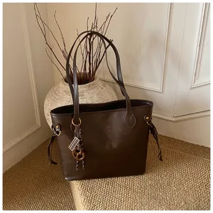 Minimalist brown commuting tote bag, detailed view showing premium leather texture and chic design.
