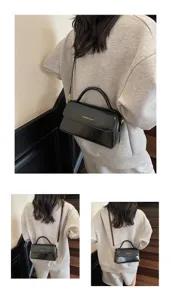 Sac bandoulière en cuir vernis noir vue détaillée avec poignée et pièces métalliques.