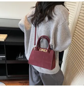 Elegante borsa in camoscio bordeaux con manico e tracolla, dal design retro versatile.