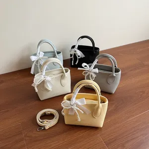 Borsa a secchiello minimalista monocolore con fiocco di perle elegante e tracolla regolabile.