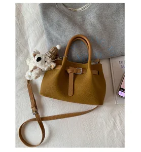 Stylish brown woven bucket bag with top handle, adjustable crossbody strap and cute bear charm.