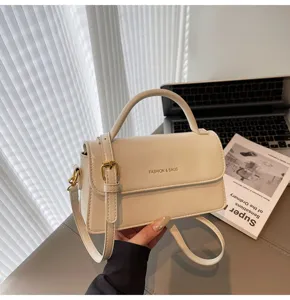 Minimalist cream top handle shoulder bag detail showcasing sleek leather and metal buckle hardware.