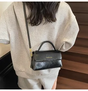 Vue detaillee en gros plan du sac a main noir en cuir vernis pour femme avec poignee.