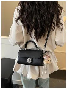 Borsa a tracolla nera in pelle con elegante chiusura a torsione e grazioso orsetto per lavoro.