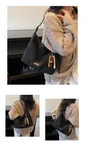 Detailed view of women's black shoulder underarm bag with wooden bead pendant charm.