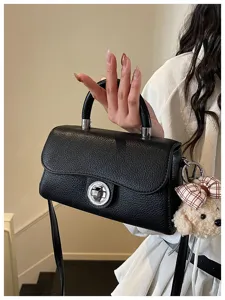 Borsa a tracolla strutturata nera con chiusura chic e ciondolo orsetto. In ecopelle testurizzata.