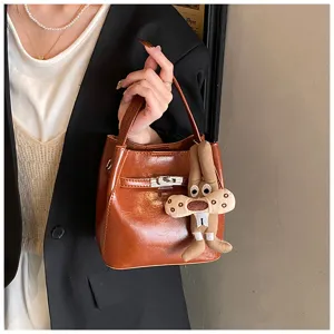 Borsa secchiello in pelle marrone con chiusura in metallo e ciondolo in peluche. Borsa elegante.