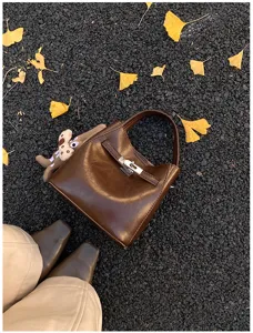 Borsa a mano marrone dettaglio in pelle, chiusura con fibbia retrò e simpatico ciondolo.