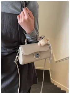 Chic borsa a tracolla beige con ciondolo orsetto, elegante borsa da giorno per donna.