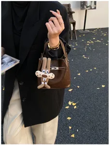 Borsa a secchiello in pelle marrone alla moda con chiusura metallica e ciondolo coniglio.