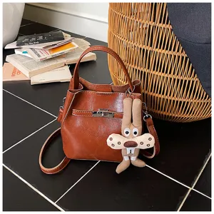 Borsa secchiello in ecopelle marrone con chiusura in metallo e ciondolo coniglio peluche.