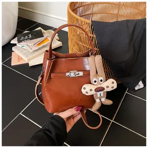 Borsa a secchiello in pelle PU marrone con chiusura a girello e ciondolo peluche di coniglio.
