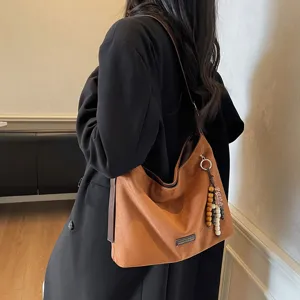 Retro suede shoulder bag for women, trendy underarm hobo bag with chic pendant for autumn.