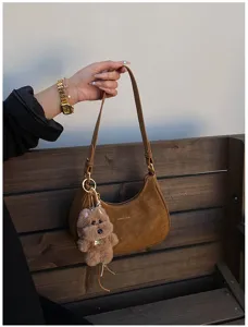 Brown suede hobo shoulder bag for women, chic dumpling bag design with plush bear charm.