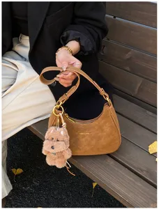 Brown suede hobo shoulder bag detail, stylish dumpling purse with cute plush dog pendant.