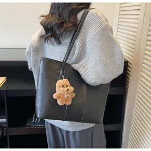 Vista dettagliata di una elegante borsa a spalla nera in pelle PU con simpatico ciondolo.