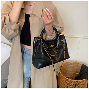 Bolso de hombro acolchado negro clásico con cadena dorada y elegante cierre de giro.