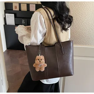Vista dettagliata dell'elegante borsa a spalla marrone retrò in pelle PU con ciondolo orsetto.