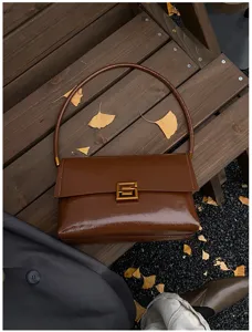 Dettaglio borsa a spalla in pelle verniciata marrone, elegante borsa in cera morbida con fibbia.