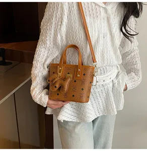 Detail view of brown retro bucket bag with vintage monogram pattern and cute bag pendant.