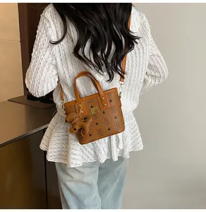 Retro brown monogram bucket bag detail, chic crossbody handbag with cute bear pendant.