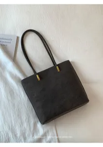 Detailansicht der dunkelgrauen minimalistischen Tasche mit goldener Hardware und Riemen.