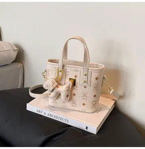 Detailed view of chic beige bucket handbag with cute bear monogram pattern and chic chain strap.