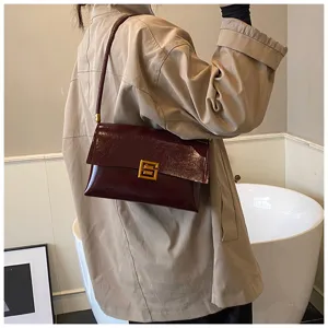 Vista dettagliata della borsa a spalla da donna in pelle cerata bordeaux con elegante fibbia dorata.