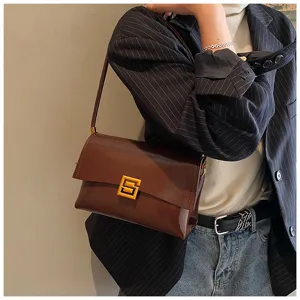 Dettaglio borsa a spalla in morbida pelle cerata marrone, elegante borsa ascellare dorata.