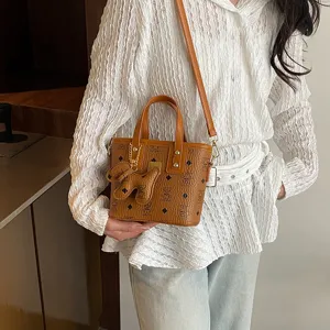 Chic retro bucket bag with top handle and crossbody strap, stylish vintage monogram design.