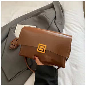 Borsa a tracolla morbida in pelle cerata marrone sotto l'ascella con chiusura dorata.