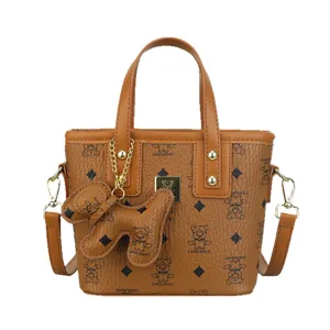 Brown leather bucket bag with top handle, crossbody strap, and cute bear pendant design.