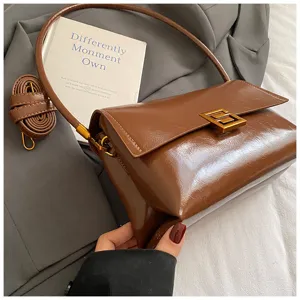 Primo piano di borsa a spalla in pelle cerata lucida con elegante chiusura metallica.