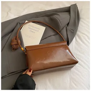 Primo piano dettagliato della borsa a spalla in pelle morbida marrone con texture fine.