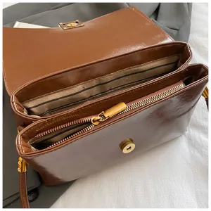 Dettaglio borsa a tracolla marrone con scomparti interni con zip e morbida texture.