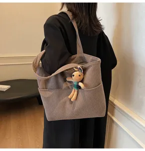 Corduroy tote bag women detail view, large capacity casual commuting handbag with cute plush charm.