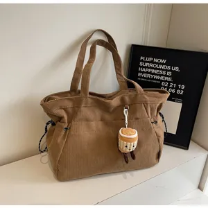 Vista dettagliata della borsa tote in velluto a coste marrone, con texture e grazioso peluche.