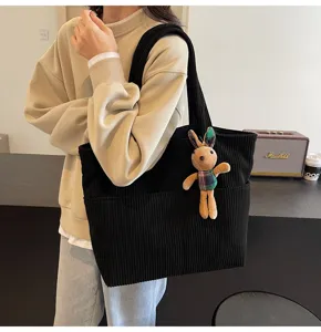 Corduroy tote bag detail view showing the front pocket and cute plush bunny rabbit pendant hanging.