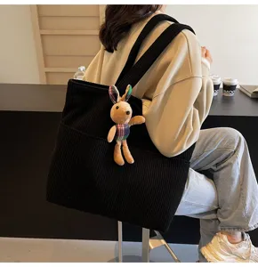 Black corduroy tote bag detail view, casual large capacity shoulder bag with cute rabbit pendant.