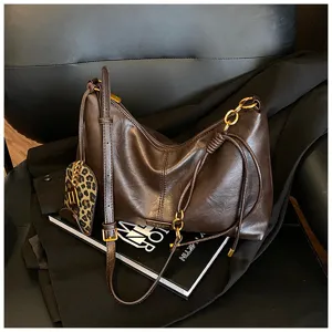 Stylish dark brown leather slouchy hobo shoulder bag with chain strap and leopard charm.