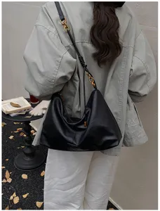 Detailed view of women's black hobo shoulder bag with stylish metal chain and knot strap.